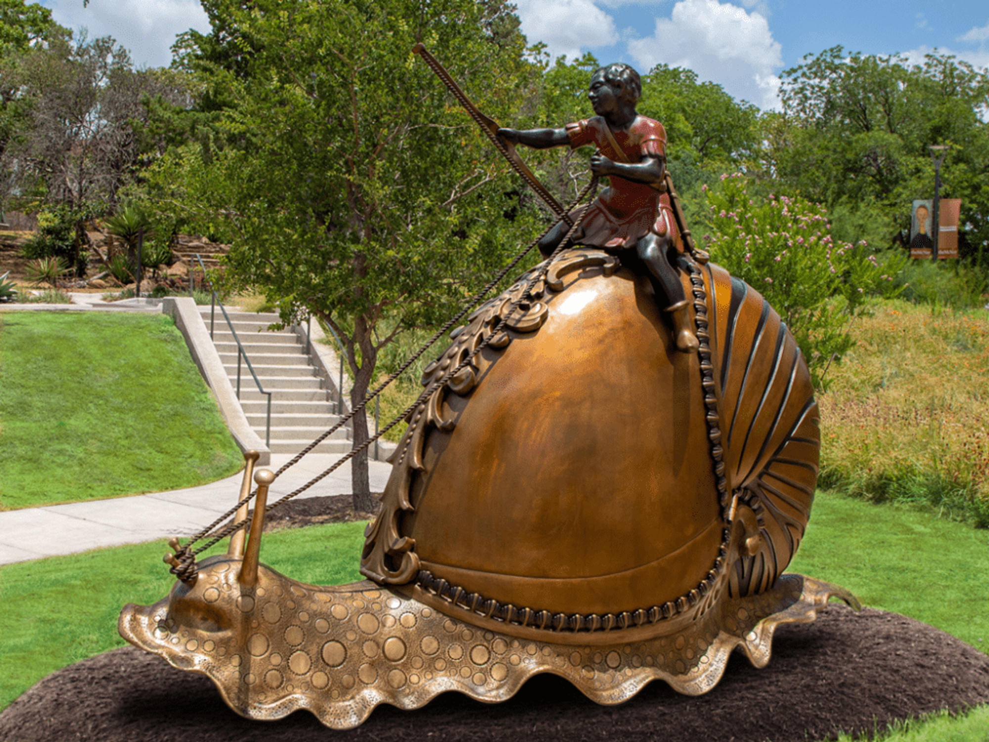 A bronze statue of a boy riding a snail with a nautilus shell stands 7 feet tall at the McNay Art Museum.