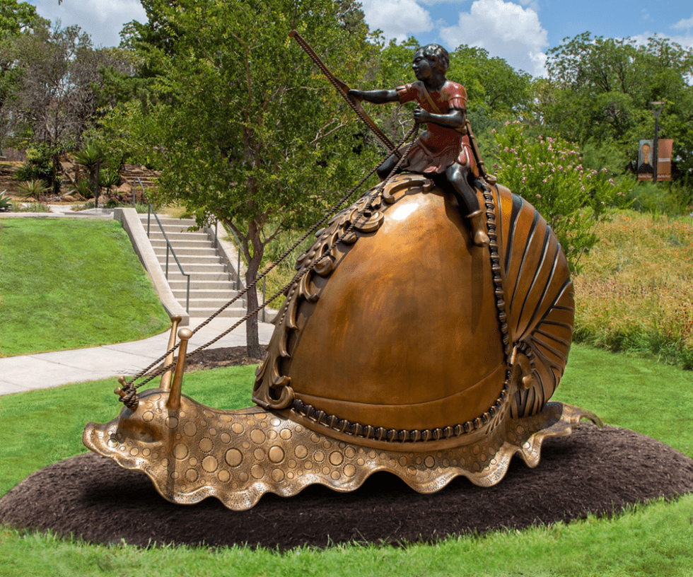 A bronze statue of a boy riding a snail with a nautilus shell stands 7 feet tall at the McNay Art Museum.