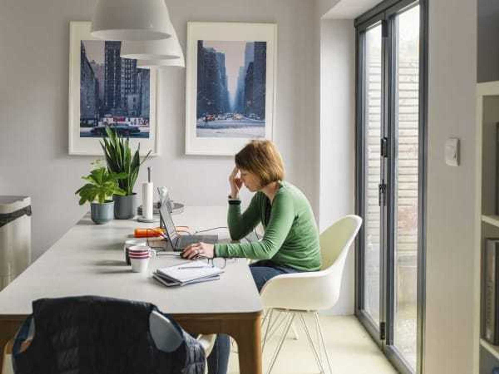 A stressed mature woman works from her dining table at home