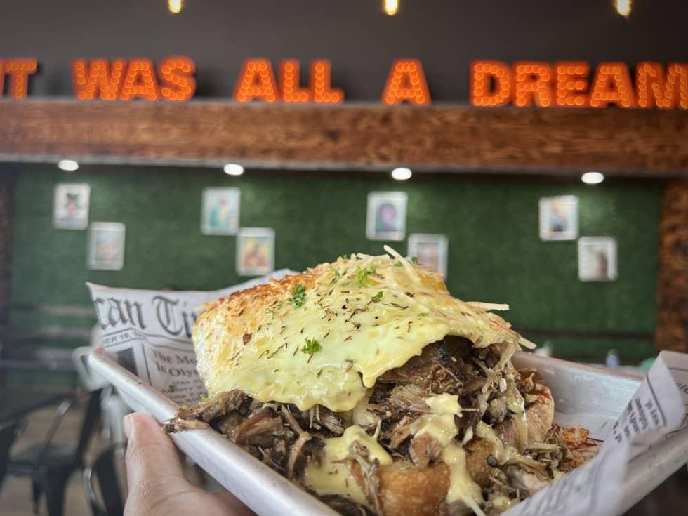 A "Texas Toast Benedict" with jerk pork in front of glowing signage spelling "it was all a dream."