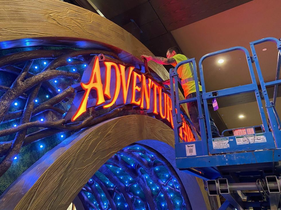 A worker puts the finishing touches on a sign.
