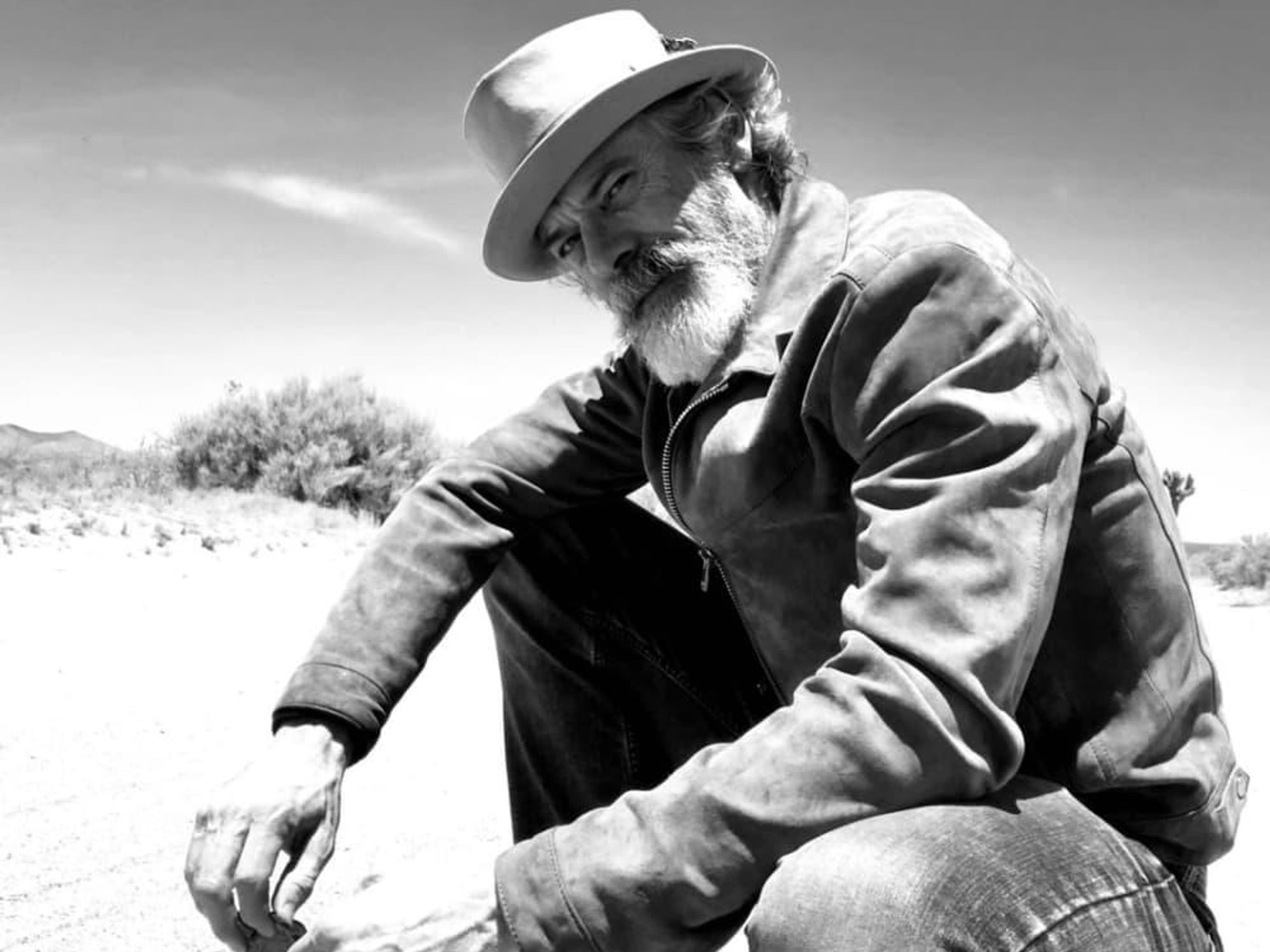 Actor and musician Tommy Howell poses in suede in a desert landscape.