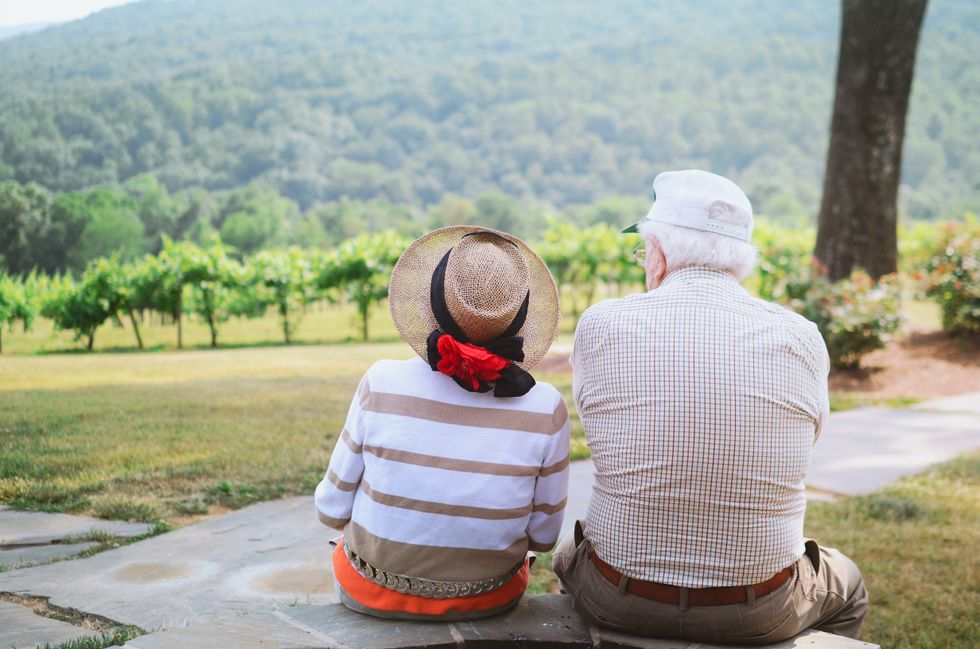 An elderly couple enjoying their backyard view of a hillside