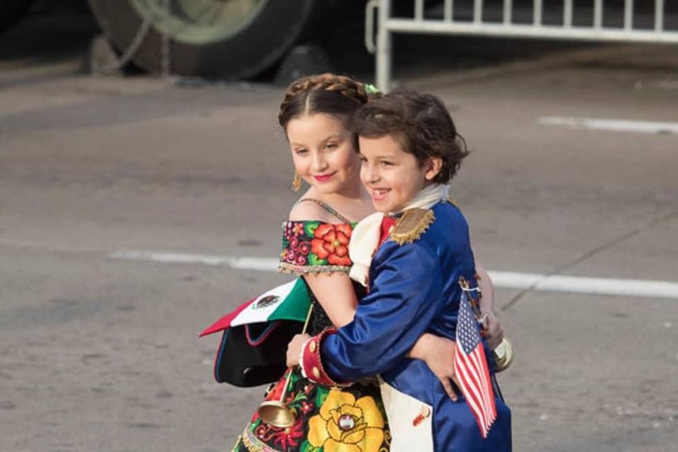 Children from Laredo and Nuevo Laredo in historical costumes exchange abrazos.