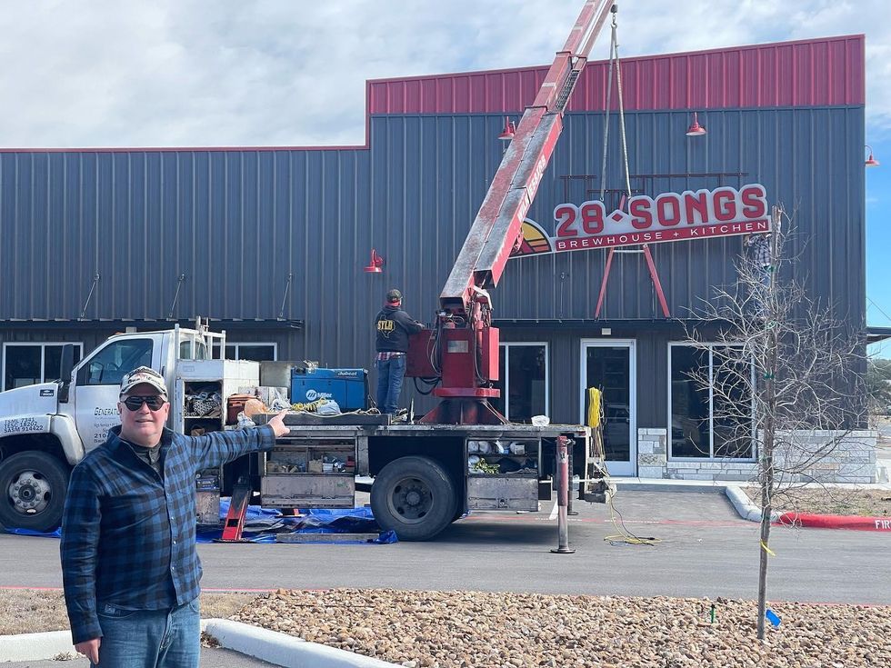 Donald Kretz, owner of 28 Songs Brewhouse and Kitchen, shows the new signage that a contractor is placing for the brewpub, which will occupy the former Main and Market building at 110 Market Ave. in Boerne. (Courtesy Boerne Kendall County Economic Development Corp.)