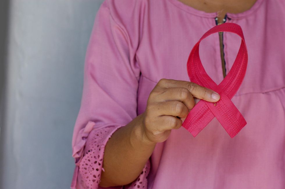Person holding pink ribbon, San Antonio breast cancer awareness.