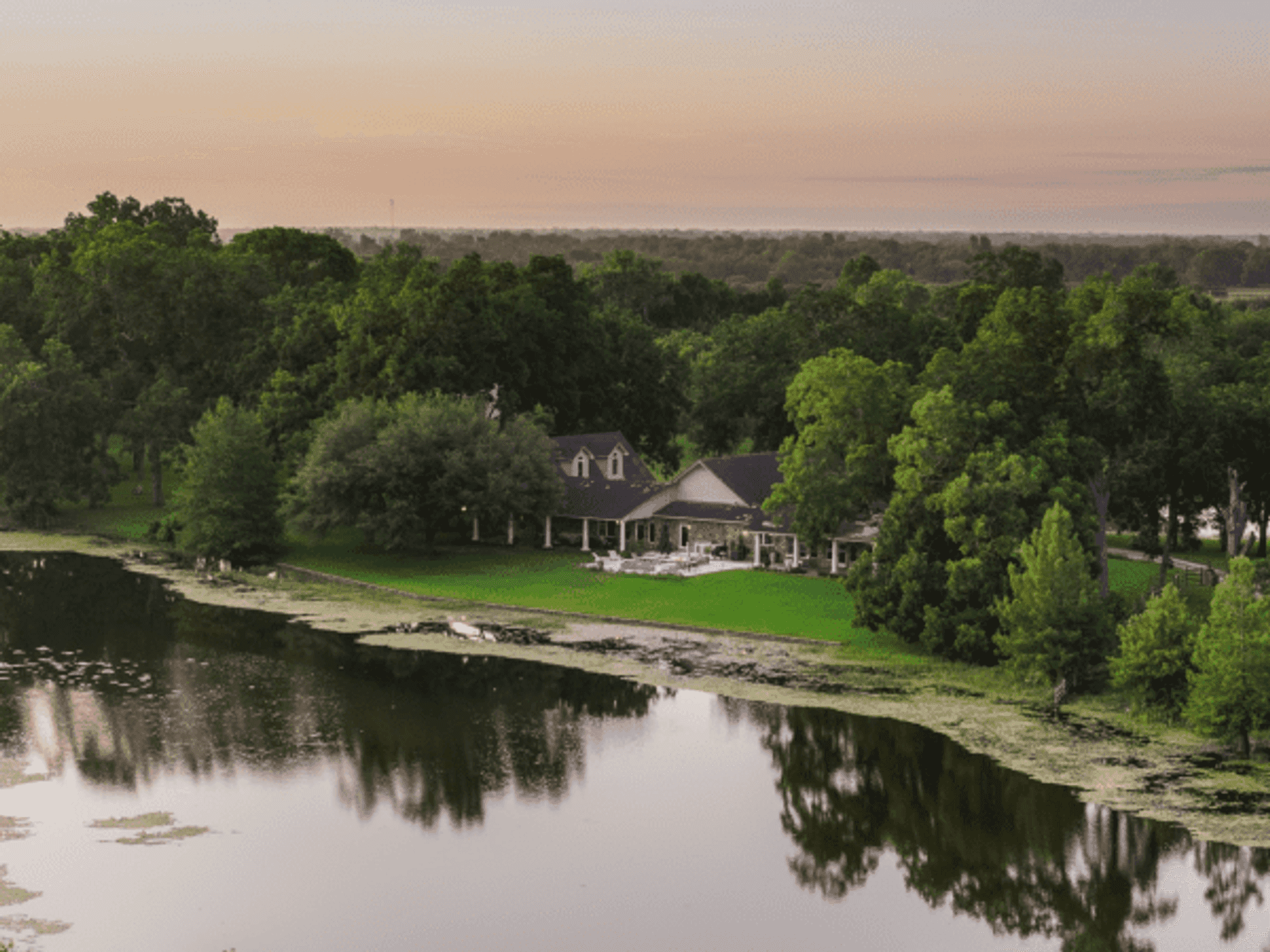 Photo of the S Lazy S ranch house, set back on a green lawn acbove a pond
