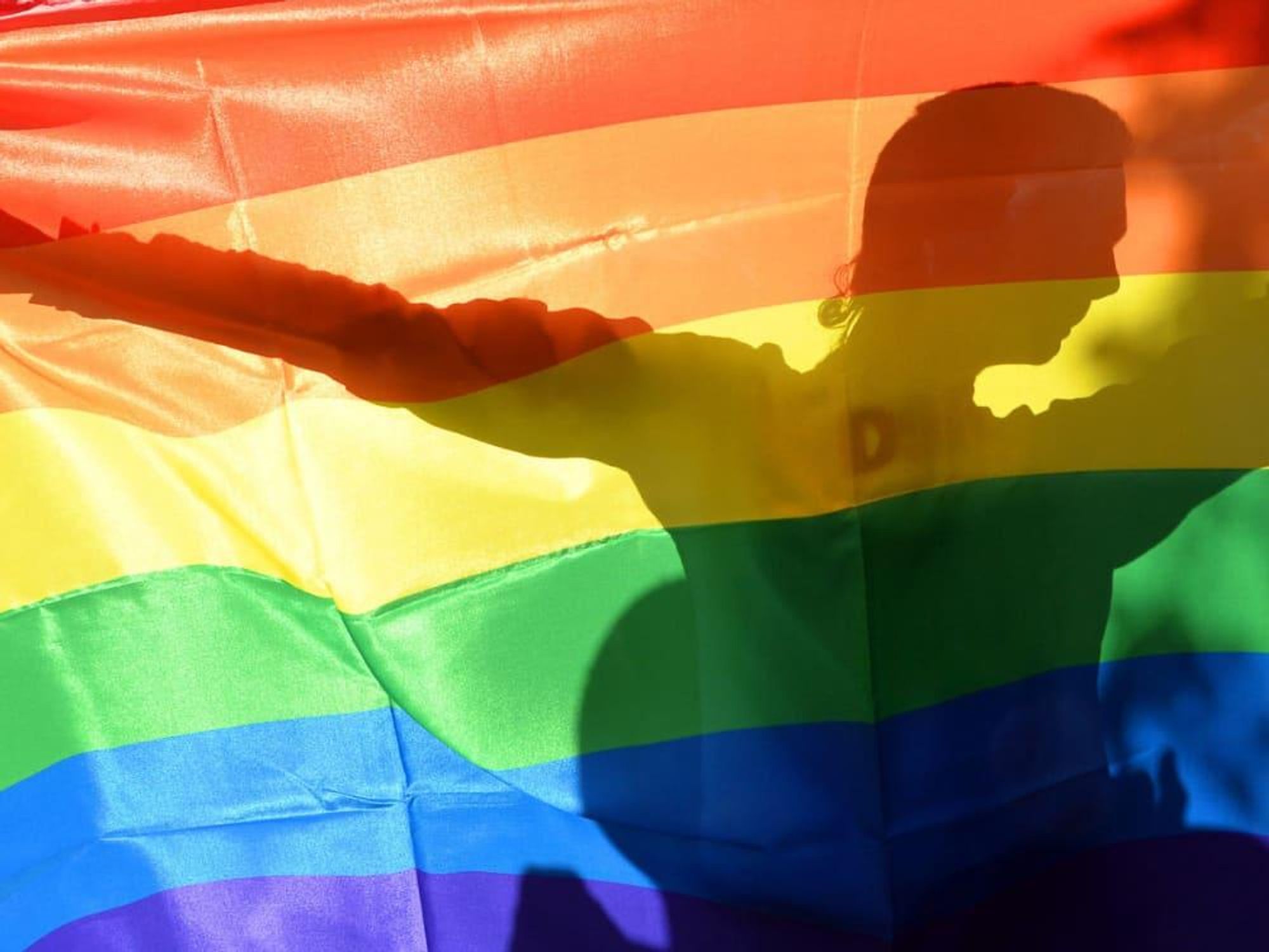 rainbow flag with person silhouetted behind it