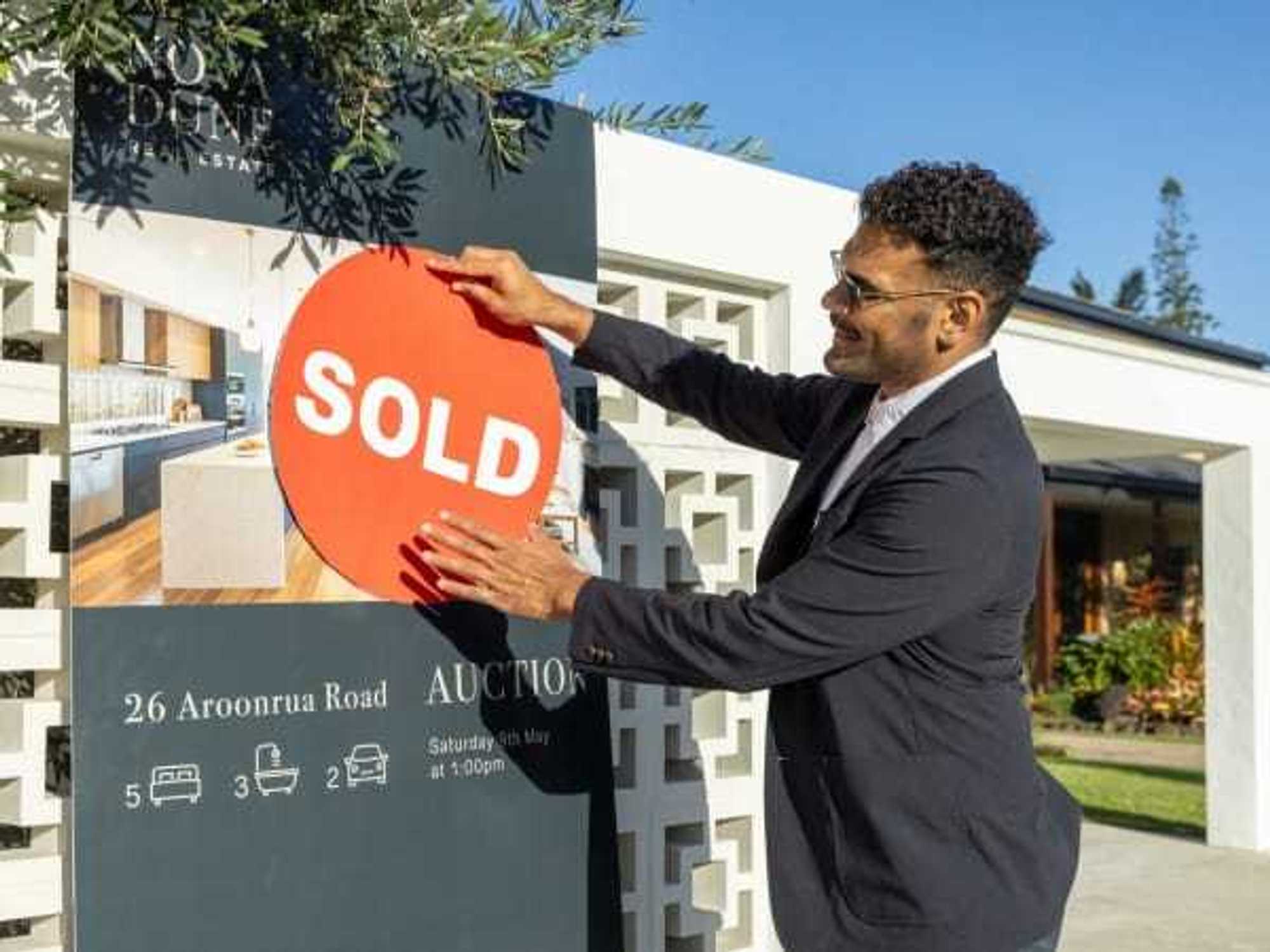 Real estate agent putting sold sign up outside house