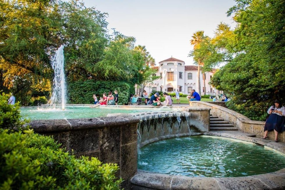 The Spanish-revival McNay mansion behind a water fountain and a crowd of visitors.